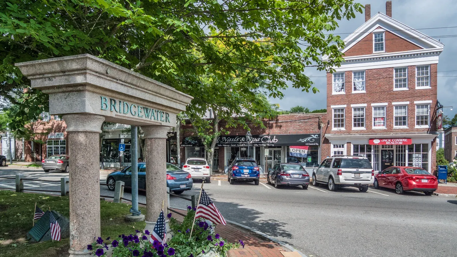The granite Bridgewater gateway marker in Central Square with brick Federal-style storefronts behind, Bridgewater, Massachusetts