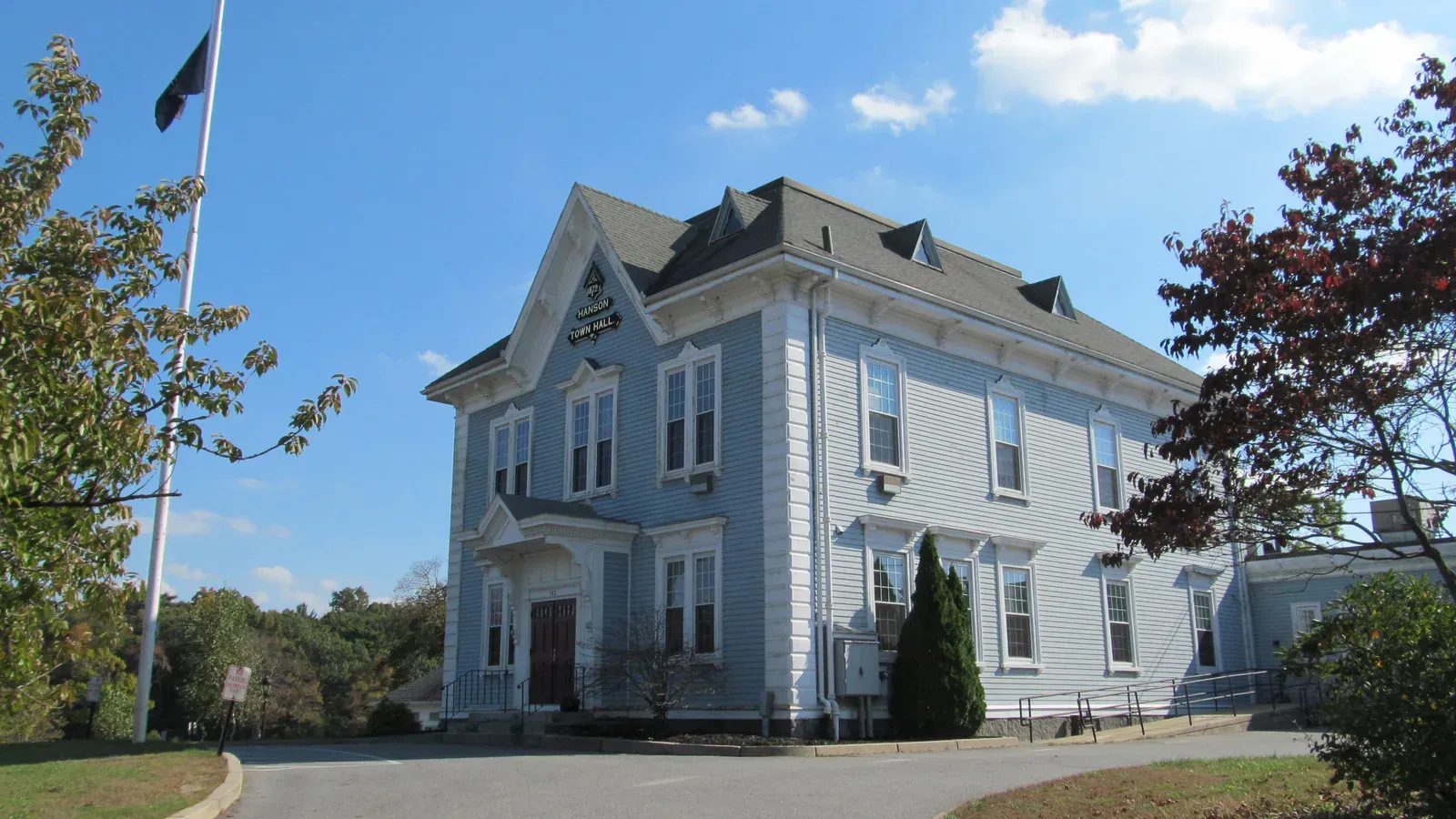 Hanson Town Hall, a pale blue clapboard Victorian building with a mansard roof and flagpole, Hanson, Massachusetts
