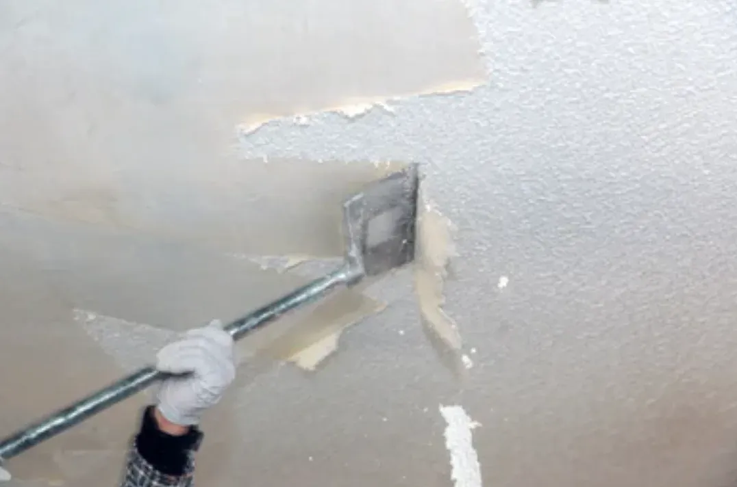 Popcorn ceiling texture being scraped off a ceiling
